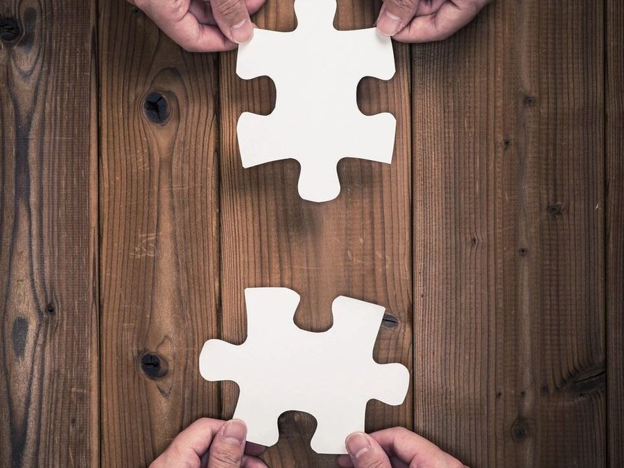 Two hands joining jigsaw pieces